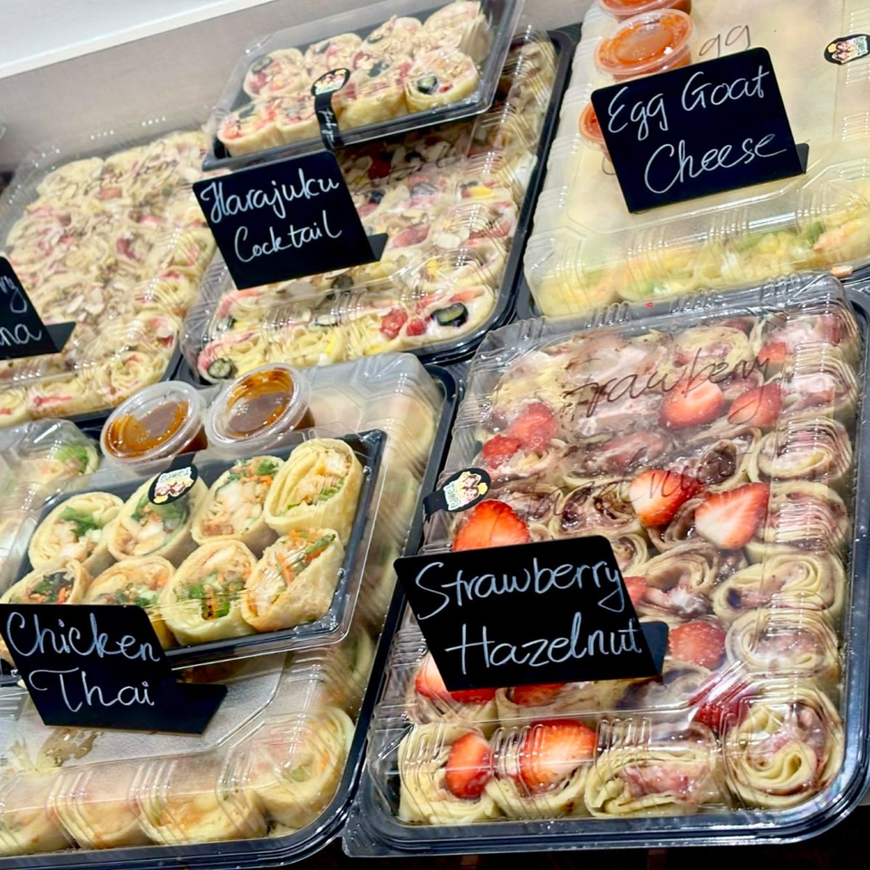 Packaged trays of savory and sweet sushi rolls labeled Harajuku Cocktail, Egg Goat Cheese, Chicken Thai, and Strawberry Hazelnut.