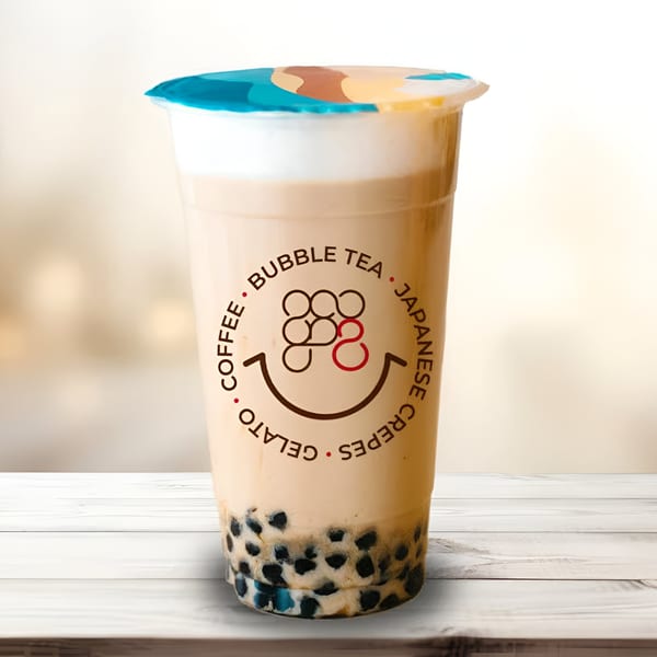 Eight Turn Crepe bubble tea with tapioca pearls and foam, on a white wooden surface.