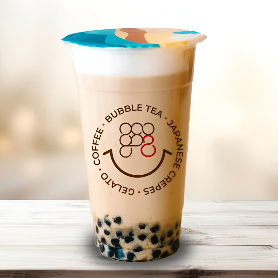 Eight Turn Crepe bubble tea with tapioca pearls and foam, on a white wooden surface.