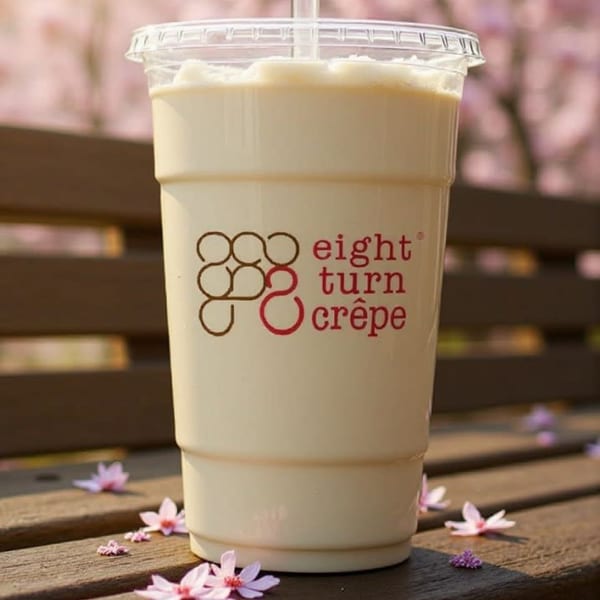 Eight Turn Crepe branded drink on a wooden bench with scattered pink petals and cherry blossoms.