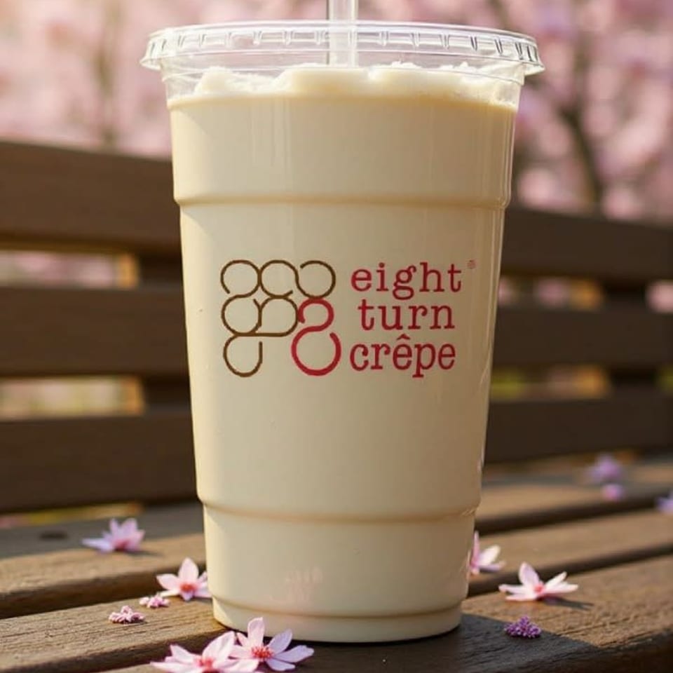 Eight Turn Crepe branded drink on a wooden bench with scattered pink petals and cherry blossoms.