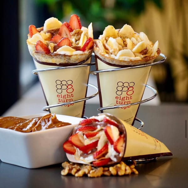 Three Eight Turn Crepes, two upright in holders, one lying down, with strawberries, bananas, and walnuts.