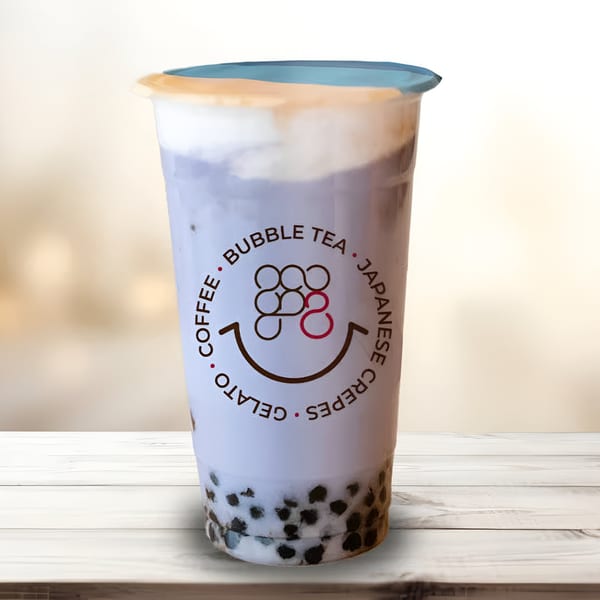 Eight Turn Crepe's purple bubble tea with tapioca pearls and a creamy topping on a wooden table.